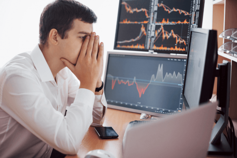 Stressed investor reviewing falling stock charts